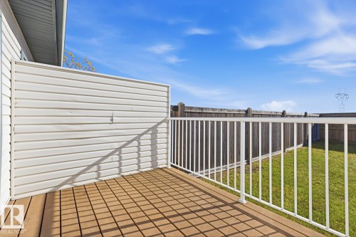 Exterior wood-finish deck with a white metal railing and a solid vinyl privacy screen - 9047 Scott Crescent Nw, Edmonton, AB 