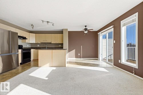 Kitchen featuring light-finish cabinetry, dark solid-surface countertops, and stainless steel appliances - 9047 Scott Crescent Nw, Edmonton, AB 
