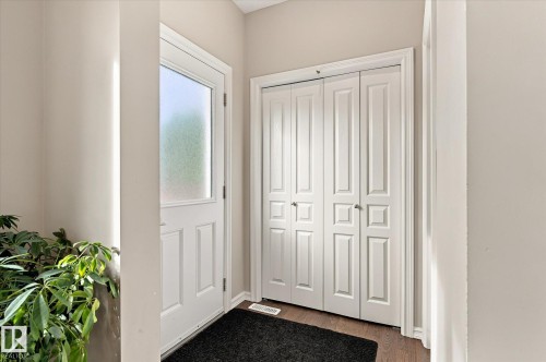 Entryway featuring a white paneled door with frosted glass, wood-finish flooring, and white bi-fold closet doors - 21935 91 Avenue Nw, Edmonton, AB 