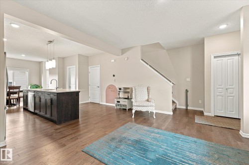 Open-concept living area featuring wood-finish flooring, recessed lighting, and a prominent kitchen island with a built-in sink and pendant lighting - 21935 91 Avenue Nw, Edmonton, AB 