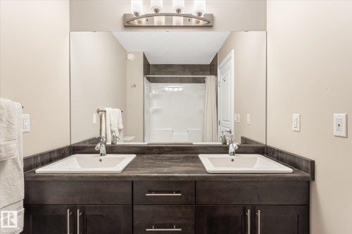 Double vanity with integrated rectangular sinks, dark wood-finish cabinetry, and brushed nickel hardware - 21935 91 Avenue Nw, Edmonton, AB 