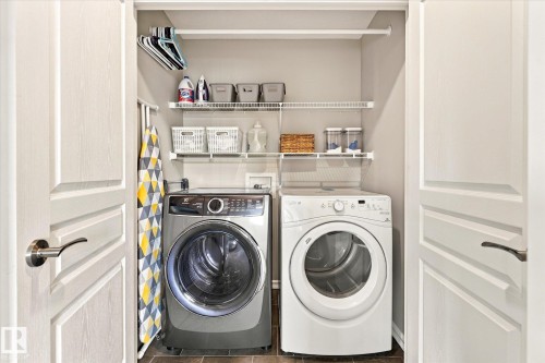 Laundry closet with a front-load washing machine, front-load dryer, wire shelving, and overhead hanging rod - 21935 91 Avenue Nw, Edmonton, AB 