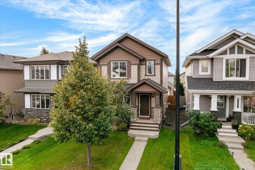 Two-story brown and tan exterior with stone accents, a covered front entry, and a concrete walkway - 21935 91 Avenue Nw, Edmonton, AB 
