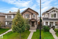 Two-story brown and tan exterior with stone accents, a covered front entry, and a concrete walkway - 