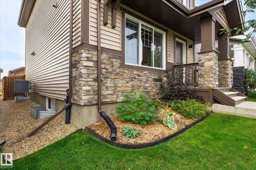 Stone veneer accents, horizontal siding, covered porch, concrete steps, and landscaped garden bed - 21935 91 Avenue Nw, Edmonton, AB 