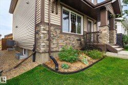 Stone veneer accents, horizontal siding, covered porch, concrete steps, and landscaped garden bed - 