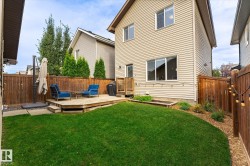 Expansive backyard featuring a manicured lawn, a wooden deck, and full privacy fencing - 