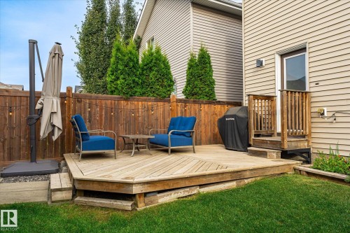 Expansive wooden deck with multi-level access, featuring a privacy fence, exterior door, and a manicured lawn - 21935 91 Avenue Nw, Edmonton, AB 