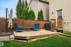 Expansive wooden deck with multi-level access, featuring a privacy fence, exterior door, and a manicured lawn - 