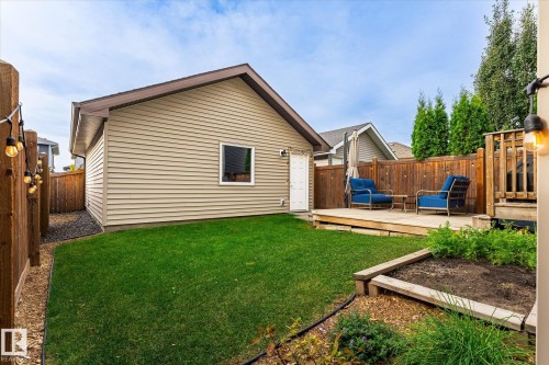 Expansive green lawn, elevated wood deck, wood privacy fencing, raised garden bed, and a detached building with horizontal siding - 21935 91 Avenue Nw, Edmonton, AB 