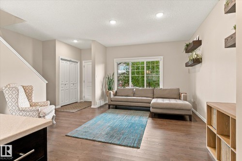 Spacious living area featuring wood-finish flooring, recessed lighting, and a large window - 21935 91 Avenue Nw, Edmonton, AB 