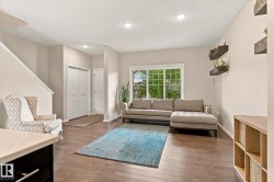 Spacious living area featuring wood-finish flooring, recessed lighting, and a large window - 