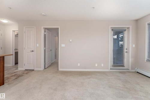 Neutral tone wall finishes, light-colored carpeting, white trim, and a glass-paneled door - #202 105 Ambleside Dr Sw, Edmonton, AB 