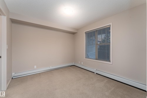 Neutral wall color, carpet flooring, window with blinds, and baseboard heating - #202 105 Ambleside Dr Sw, Edmonton, AB 