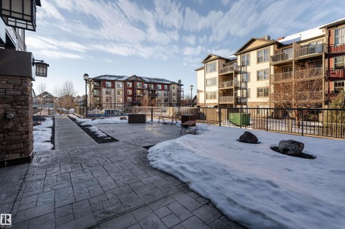 Stamped concrete patio, stone column exterior, exterior lighting fixture, black metal fencing, adjacent landscaping - #202 105 Ambleside Dr Sw, Edmonton, AB 