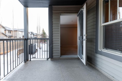 Covered balcony featuring a concrete surface, black metal railings, and direct access to an interior space - #202 105 Ambleside Dr Sw, Edmonton, AB 