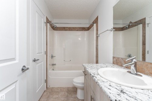 White vanity with a large oval sink, chrome faucet, and speckled countertop - #403 105 Ambleside Dr Sw, Edmonton, AB 