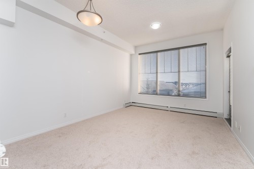 Wall-to-wall carpeting, large window with horizontal blinds, overhead light fixture, and recessed lighting - #403 105 Ambleside Dr Sw, Edmonton, AB 