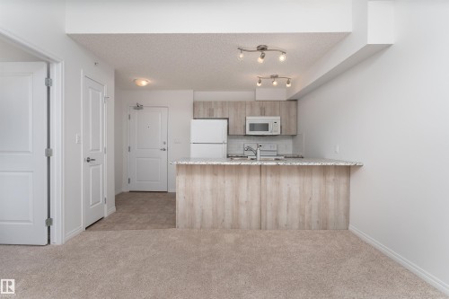 Kitchen featuring light wood-finish cabinetry, stainless steel appliances, and a light-toned backsplash - #403 105 Ambleside Dr Sw, Edmonton, AB 