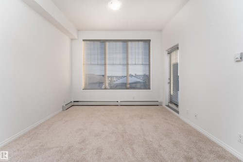 Carpeted room with a large window and a glass-paneled door - #403 105 Ambleside Dr Sw, Edmonton, AB 