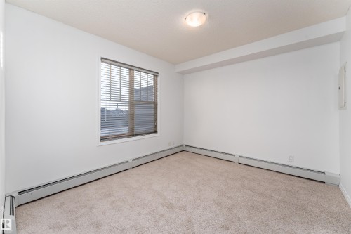 Neutral-toned carpeting, white walls, and a window with horizontal blinds - #403 105 Ambleside Dr Sw, Edmonton, AB 