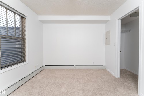 Carpeted flooring, white painted walls, window with horizontal blinds, built-in closet with track lighting, and a white interior door - #403 105 Ambleside Dr Sw, Edmonton, AB 