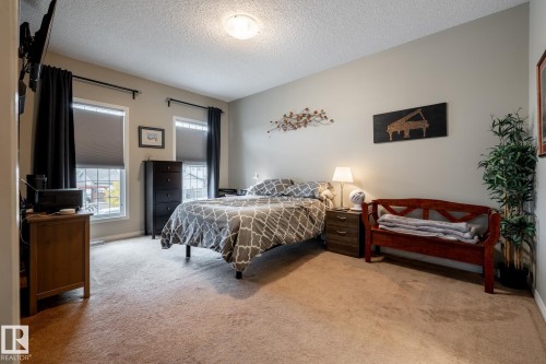 Neutral interior space featuring wall-to-wall carpeting, two dual-pane windows, and a central ceiling-mounted light fixture - 2093 Chalmers Way Sw, Edmonton, AB 