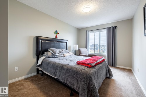 Neutral-toned walls, plush wall-to-wall carpeting, large window with natural light, and ceiling-mounted light fixture - 2093 Chalmers Way Sw, Edmonton, AB 