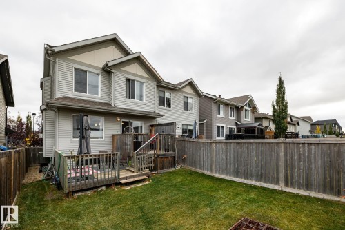 Two-story exterior featuring horizontal siding, a gabled roofline, an elevated wooden deck, and a fenced backyard with grass lawn - 2093 Chalmers Way Sw, Edmonton, AB 