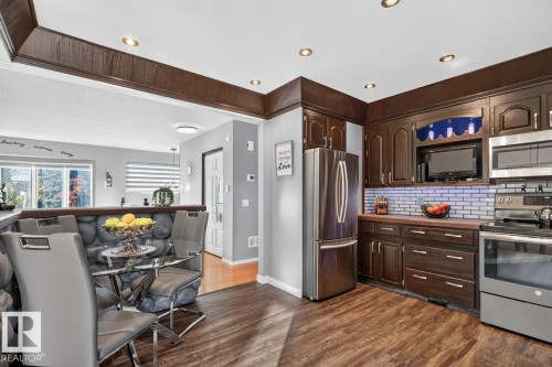 Kitchen featuring stainless steel appliances, dark wood-finish cabinetry, and wood-finish countertops - 5502 48 Avenue, Beaumont, AB 