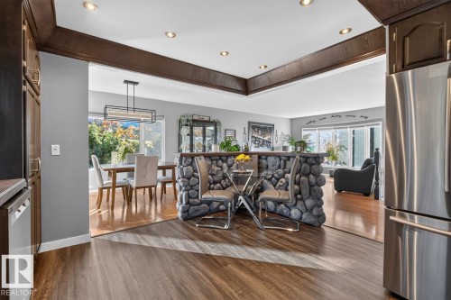 Wood-finish flooring, recessed lighting, stone-clad island, stainless steel refrigerator, and ample natural light - 5502 48 Avenue, Beaumont, AB 