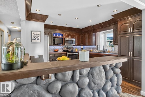 Kitchen featuring wood-finish cabinetry, recessed lighting, and a subway tile backsplash - 5502 48 Avenue, Beaumont, AB 