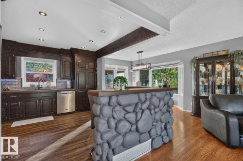 Wood-finish flooring throughout, dark wood-finish cabinetry, stainless steel appliances, decorative tile backsplash, and recessed lighting - 5502 48 Avenue, Beaumont, AB 