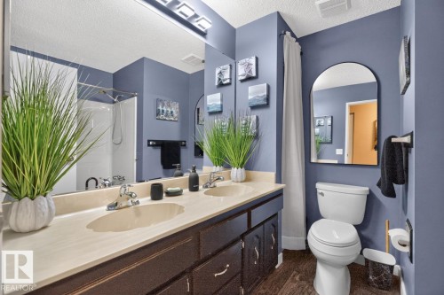 Double vanity with integrated sinks, extensive countertop space, dark wood-finish cabinetry, and a full-width mirror - 5502 48 Avenue, Beaumont, AB 