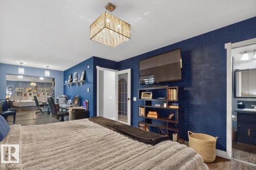 Spacious room featuring a decorative overhead light fixture, wood-finish flooring, and a mirrored wall - 5502 48 Avenue, Beaumont, AB 