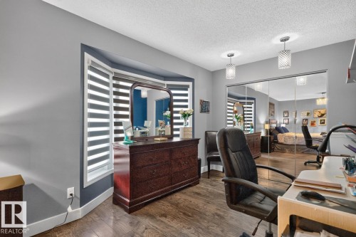 Wood-finish flooring, bay window, two contemporary pendant light fixtures, and a mirrored closet - 5502 48 Avenue, Beaumont, AB 