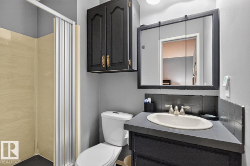 Shower enclosure with accordion door, tile vanity countertop, integrated sink, and wall-mounted medicine cabinet - 5502 48 Avenue, Beaumont, AB 