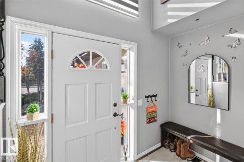 Entryway with a white paneled door featuring a decorative arched window, complemented by a sidelight window - 5502 48 Avenue, Beaumont, AB 
