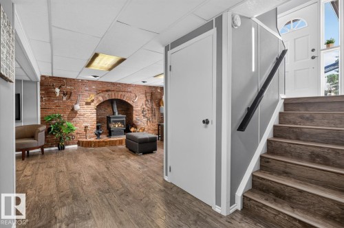 Brick archway with a built-in wood stove, wood-finish flooring, drop ceiling, and a white paneled door - 5502 48 Avenue, Beaumont, AB 
