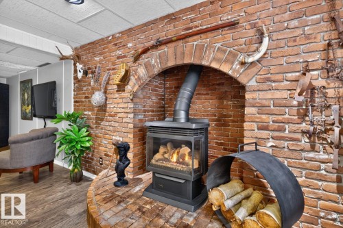 Brick feature wall with arched fireplace, wood-finish flooring, and a drop ceiling - 5502 48 Avenue, Beaumont, AB 
