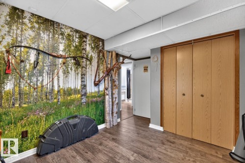 Wood-finish flooring with light-toned bi-fold closet doors, recessed lighting, and a decorative wall covering - 5502 48 Avenue, Beaumont, AB 