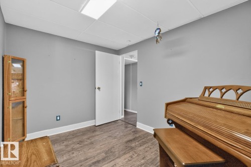 Wood-finish flooring with white trim, light gray walls, and white ceiling panels - 5502 48 Avenue, Beaumont, AB 