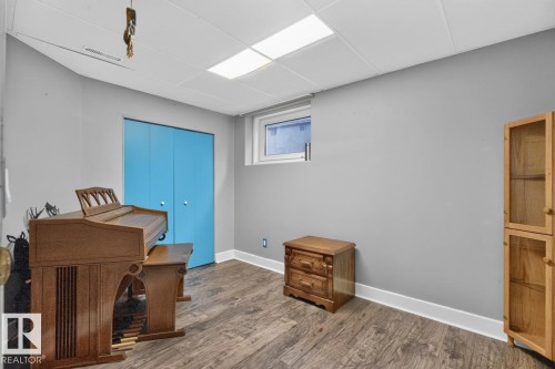 Wood-finish flooring, drop ceiling with flush-mounted lighting, and a window providing natural light - 5502 48 Avenue, Beaumont, AB 