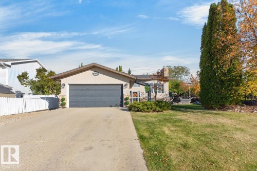 Neutral-toned exterior with a prominent two-car garage, concrete driveway, and front lawn - 5502 48 Avenue, Beaumont, AB 