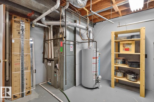 Basement utility area featuring a water heater, furnace, and exposed ceiling joists - 5502 48 Avenue, Beaumont, AB 
