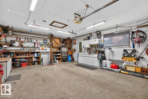 Spacious garage with concrete flooring, multiple built-in storage shelves, and overhead lighting - 5502 48 Avenue, Beaumont, AB 