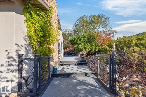Decked pathway with a stone exterior wall and established landscaping - 5502 48 Avenue, Beaumont, AB 