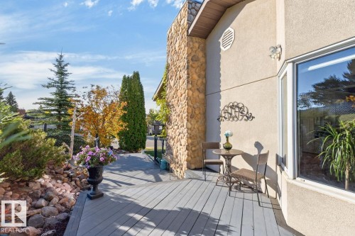 Exterior deck with composite decking, a stone-clad architectural feature, stucco siding, and an expansive window - 5502 48 Avenue, Beaumont, AB 