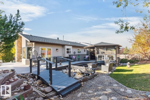 Expansive backyard featuring a multi-level deck, a screened-in structure, and a decorative bridge over a rock garden - 5502 48 Avenue, Beaumont, AB 