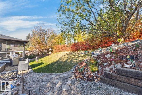 Screened-in patio with a built-in grill station, paver patio, sloped lawn, and tiered landscaping - 5502 48 Avenue, Beaumont, AB 